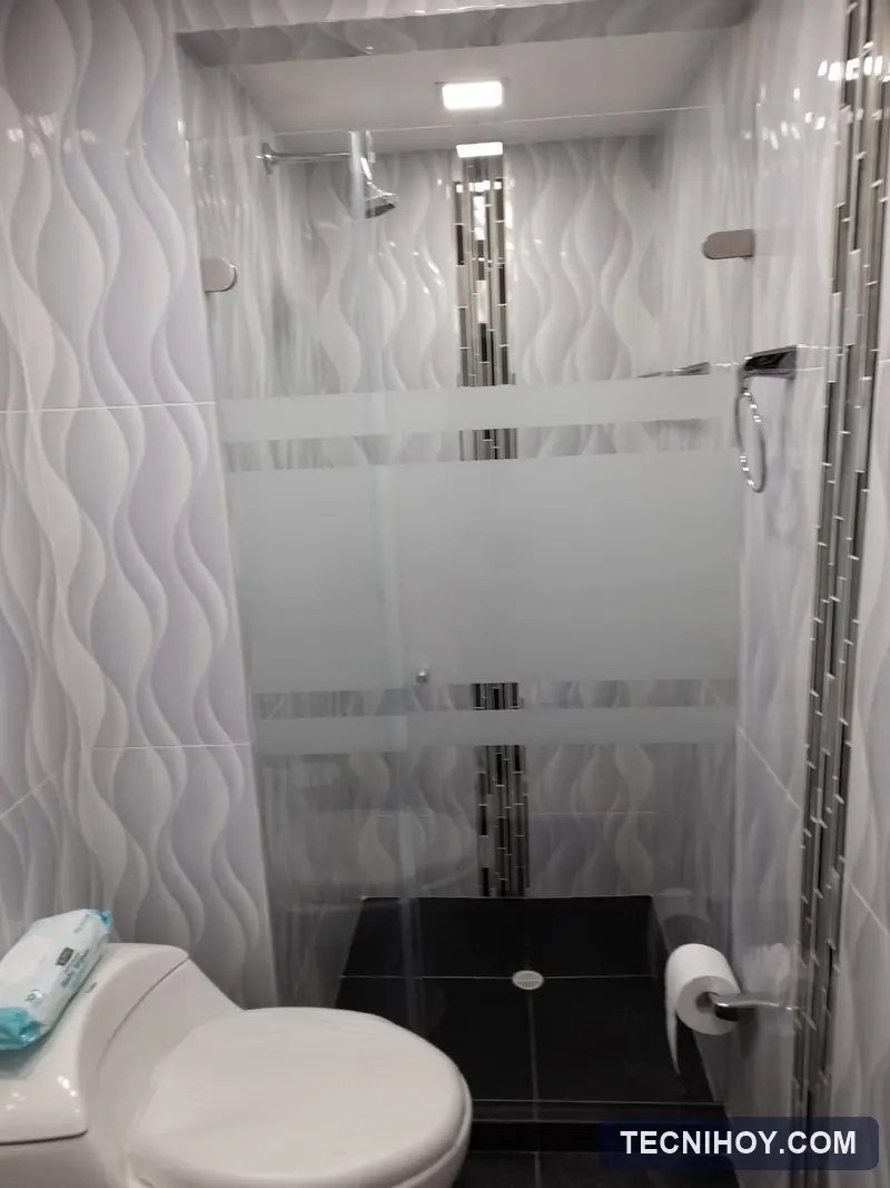 División de baño batiente en vidrio templado con franjas en sandblasting