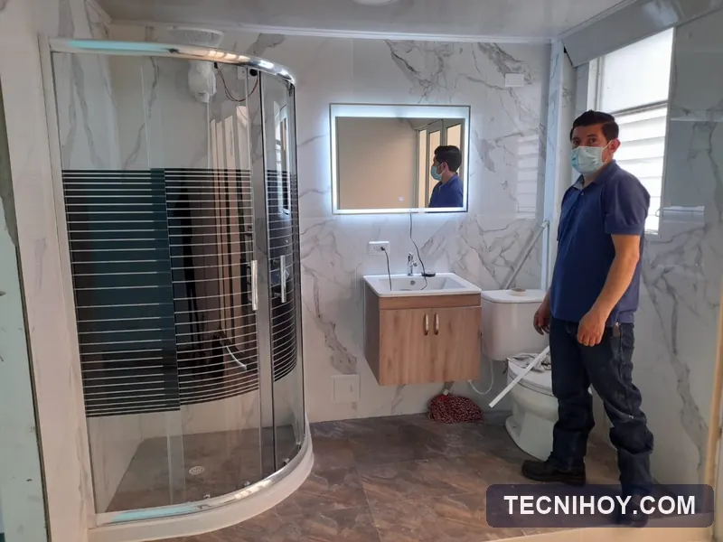 Técnico de Tecnihoy junto a una cabina de ducha en vidrio y espejo con luz LED